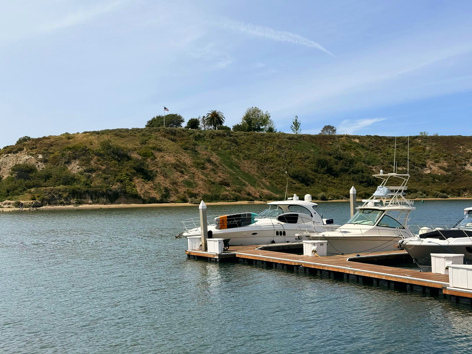 Boats at the Bayside Village docks with the Castaways bluff, its flagpole, and a lone palm across the channel