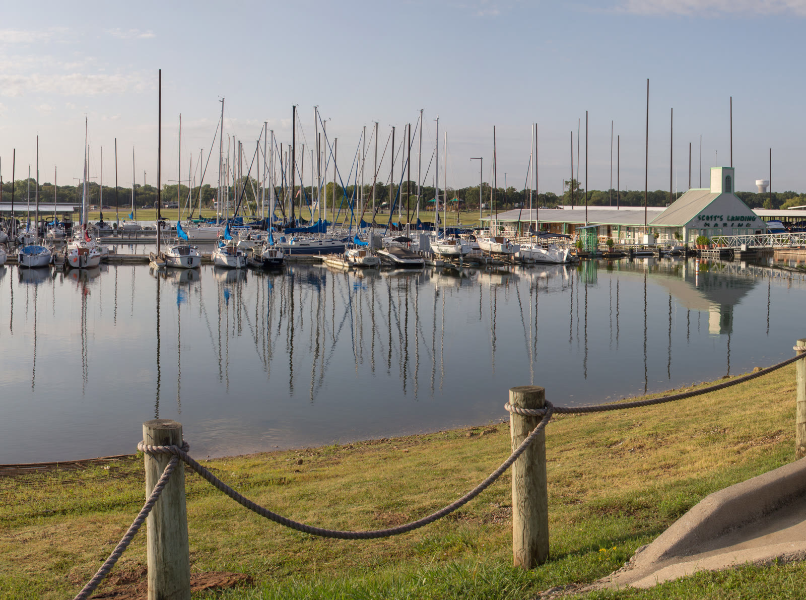 Rows of sailboats and covered slip structures reflected in glassy morning water on Grapevine Lake